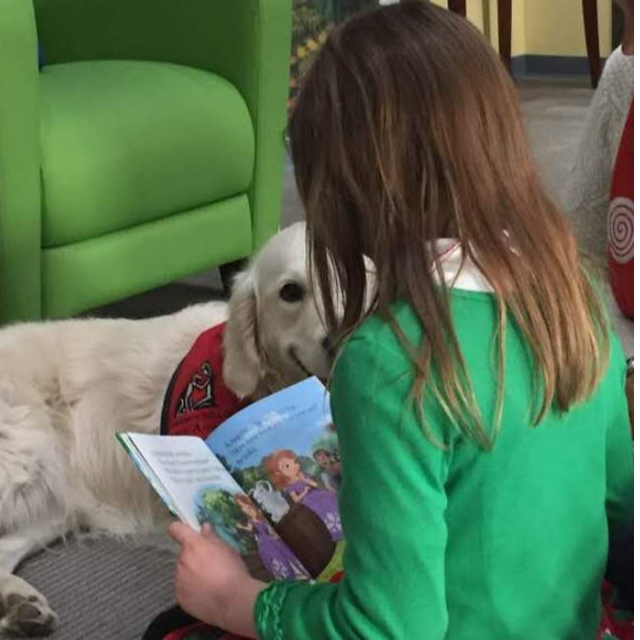 Lucy the dog with girl reading a book to her