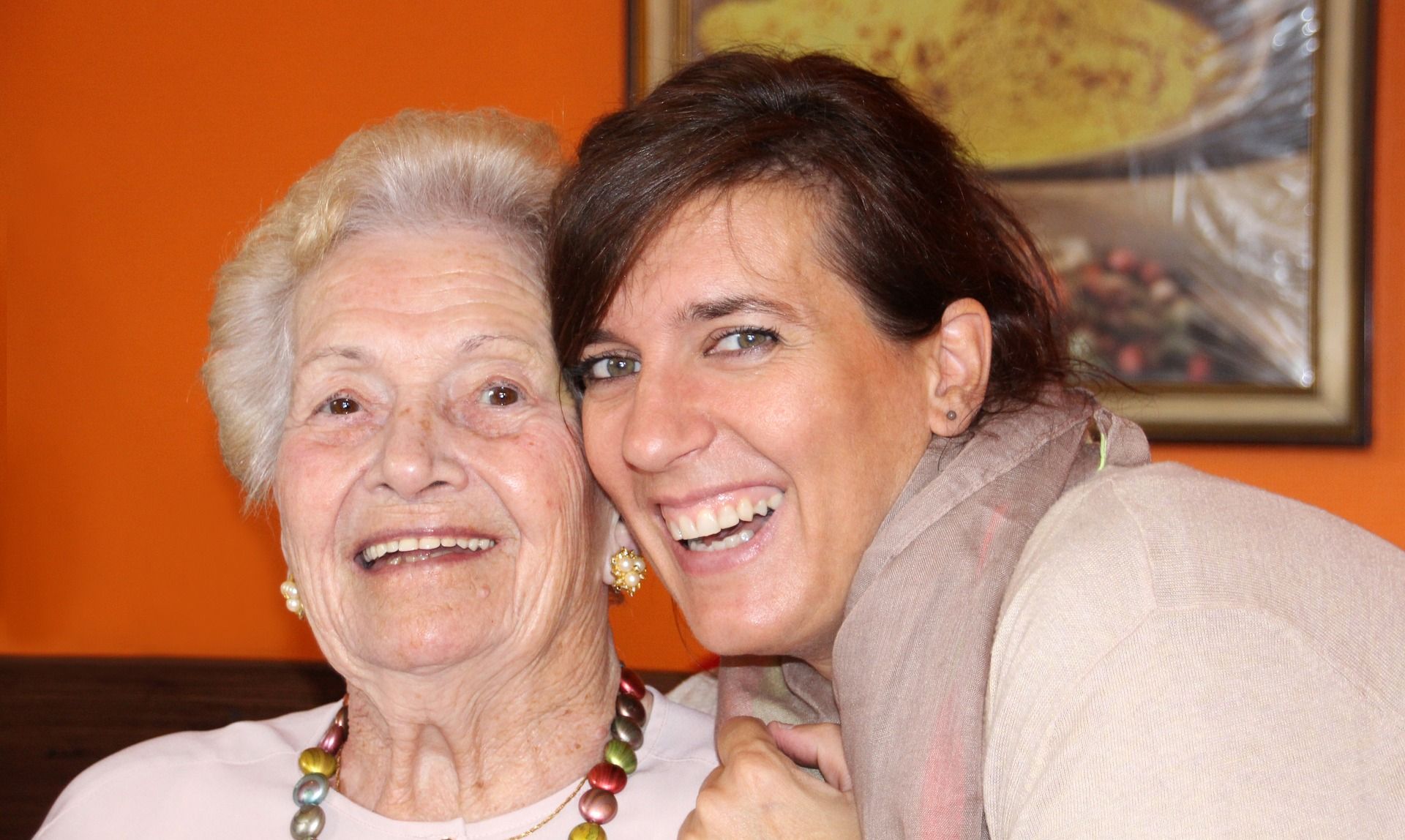 Elderly female being hugged by younger female headshot, both smiling