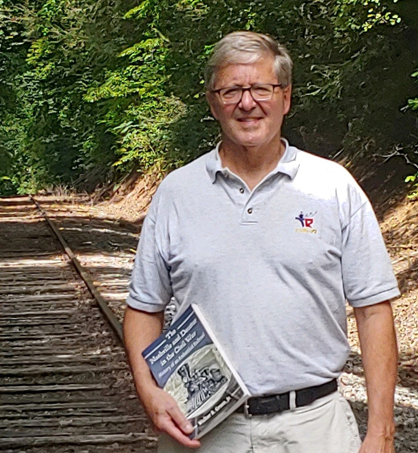 Walter R. Green, Jr photo on railroad track holding his book