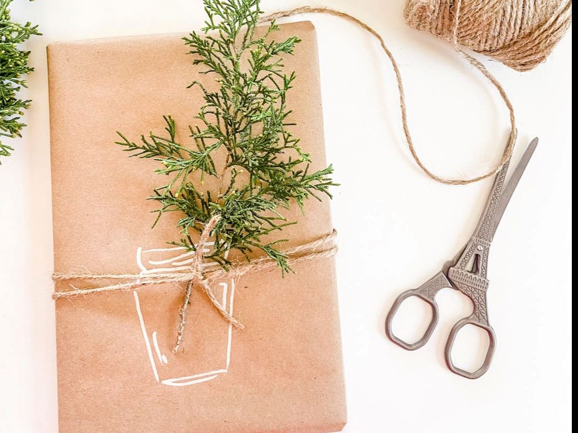 DIY gift wrapped with plain paper that has a jar drawn on it, spruce sprig, scissors, twine