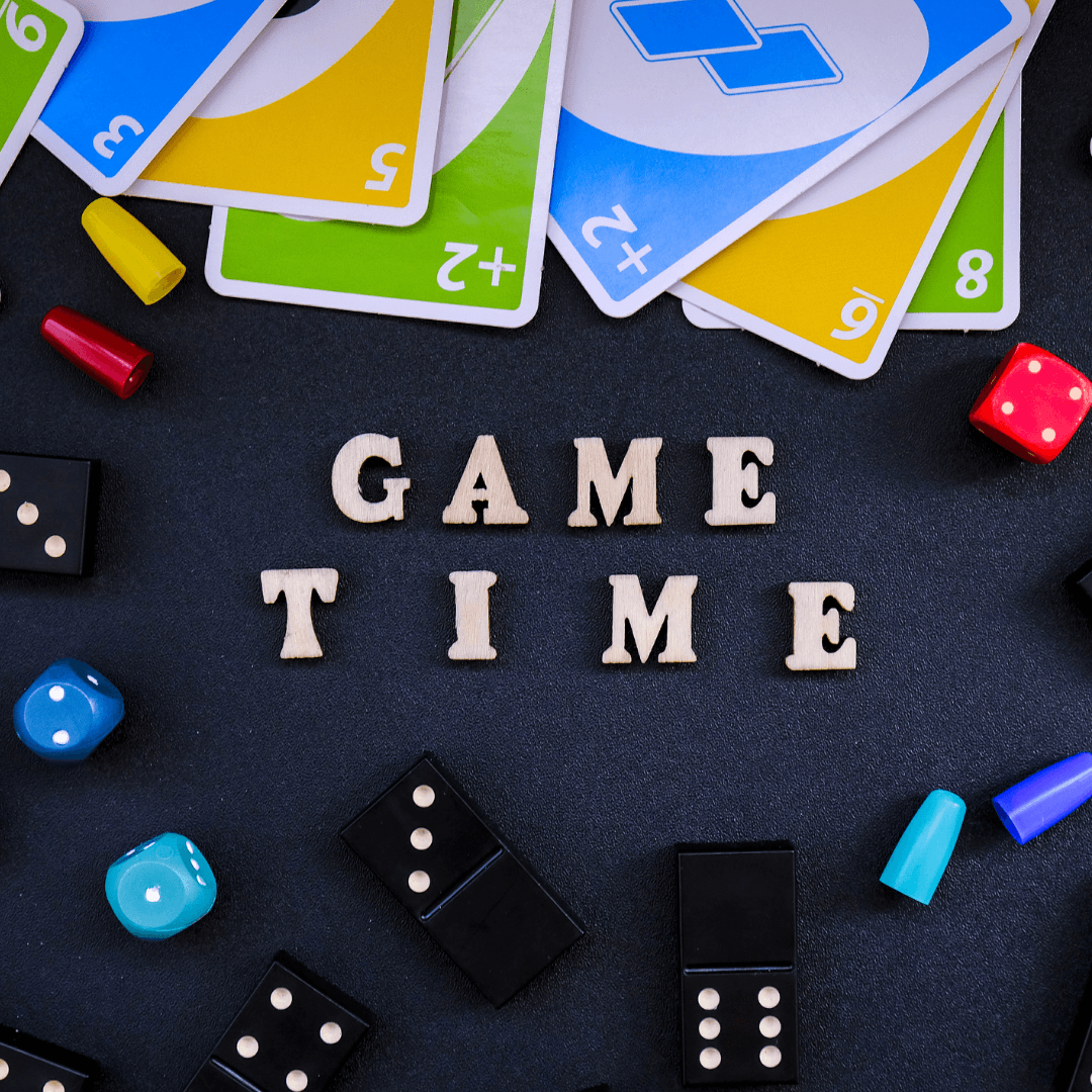 photo of letters spelling game time surrounded by dominos, game pegs, and uno cards