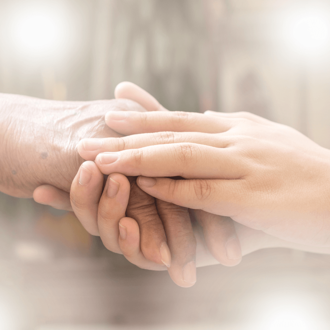 younger hands holding an older hand in soft focus
