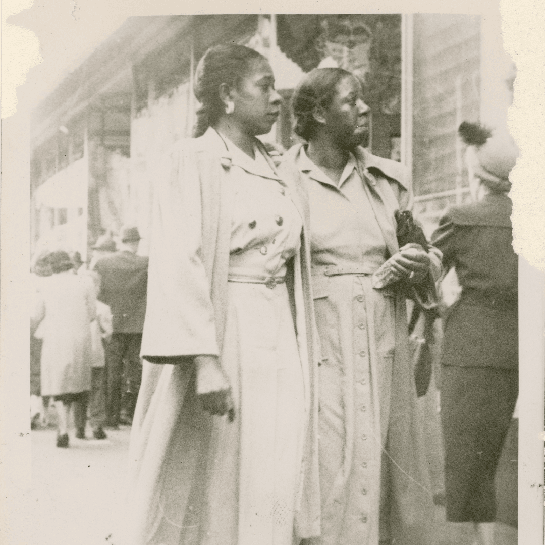 Old sepia photograph of two stylish African American women walking together on astreet