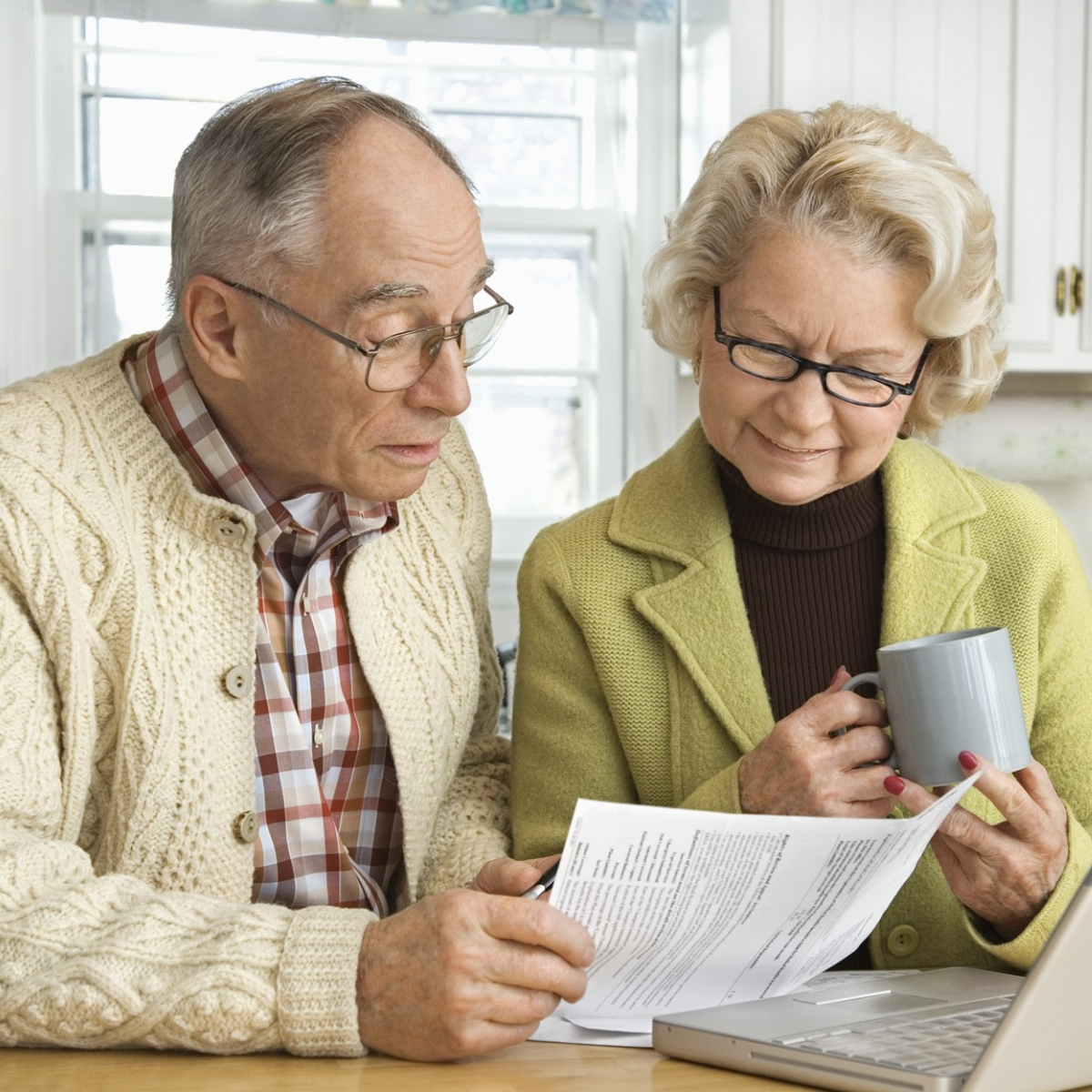 Senior Couple in Kitchen looking at papers and a laptop 