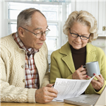 Senior Couple in Kitchen looking at papers and a laptop 